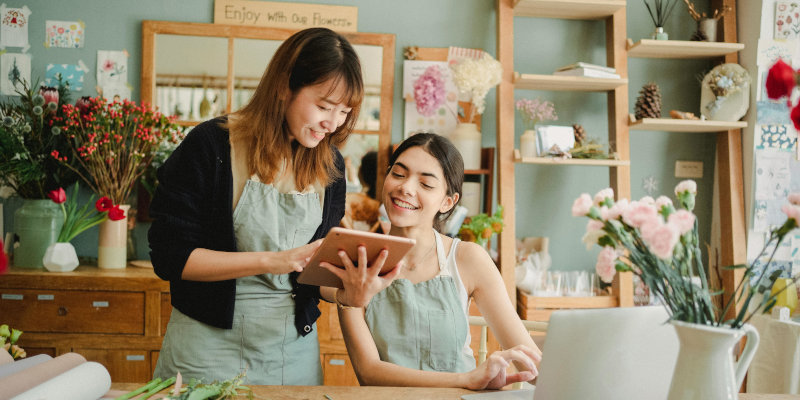 Business insurance - Two women at work, viewing a tablet.