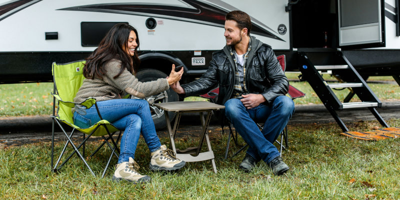 RV Insurance - Couple sitting in lawn chairs outside their travel trailer.